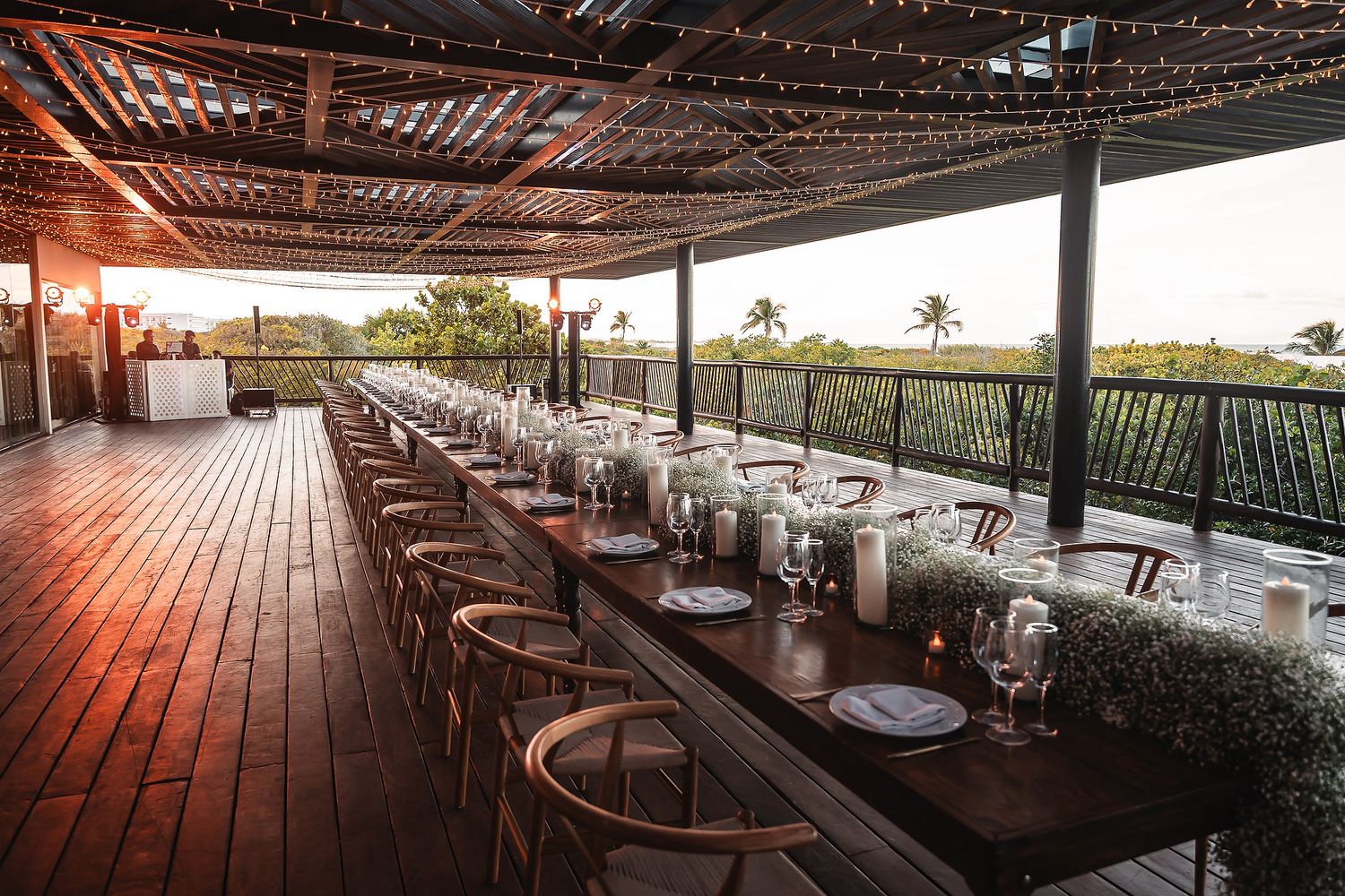 Wedding reception venue with covered deck and string lights overlooking tropical landscape.