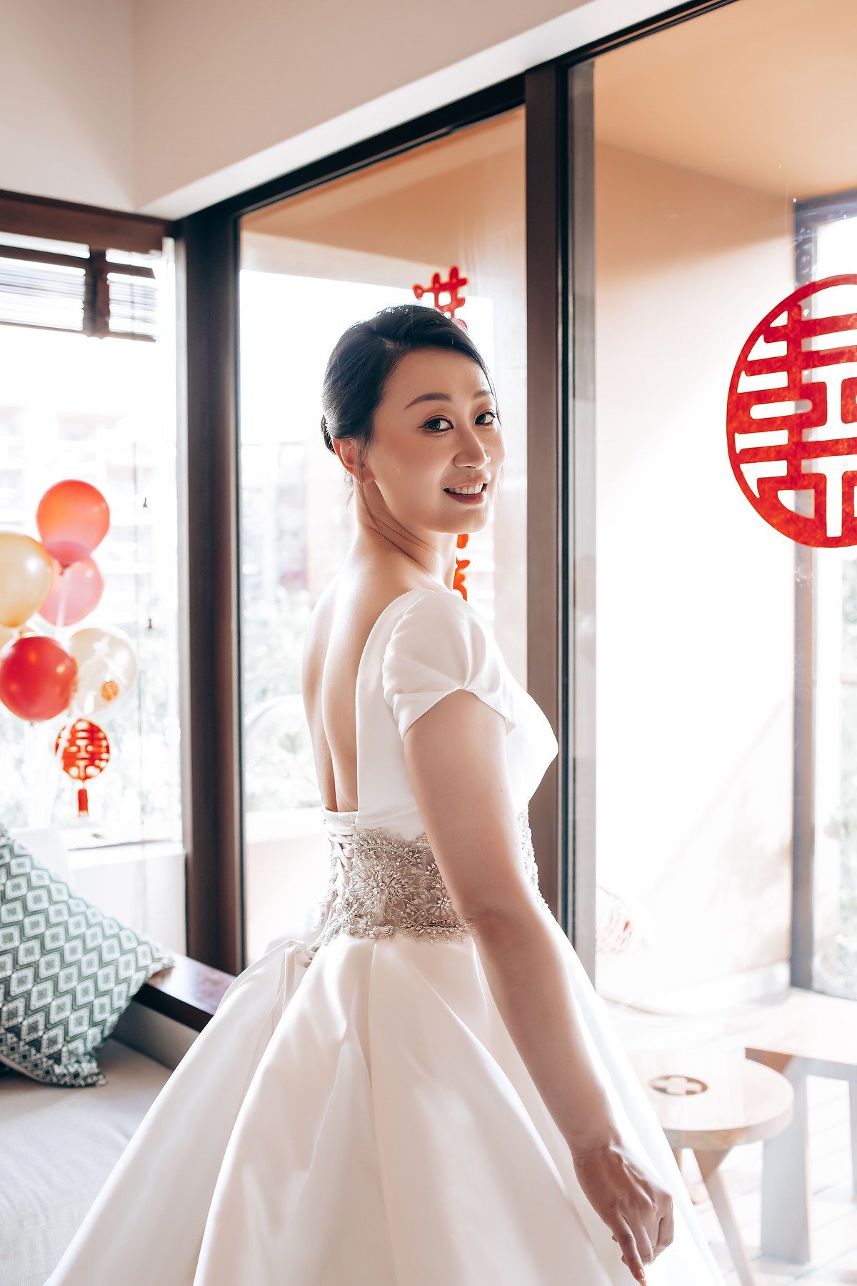 A beautiful white wedding gown with ornate beading displayed near traditional Chinese decorations.