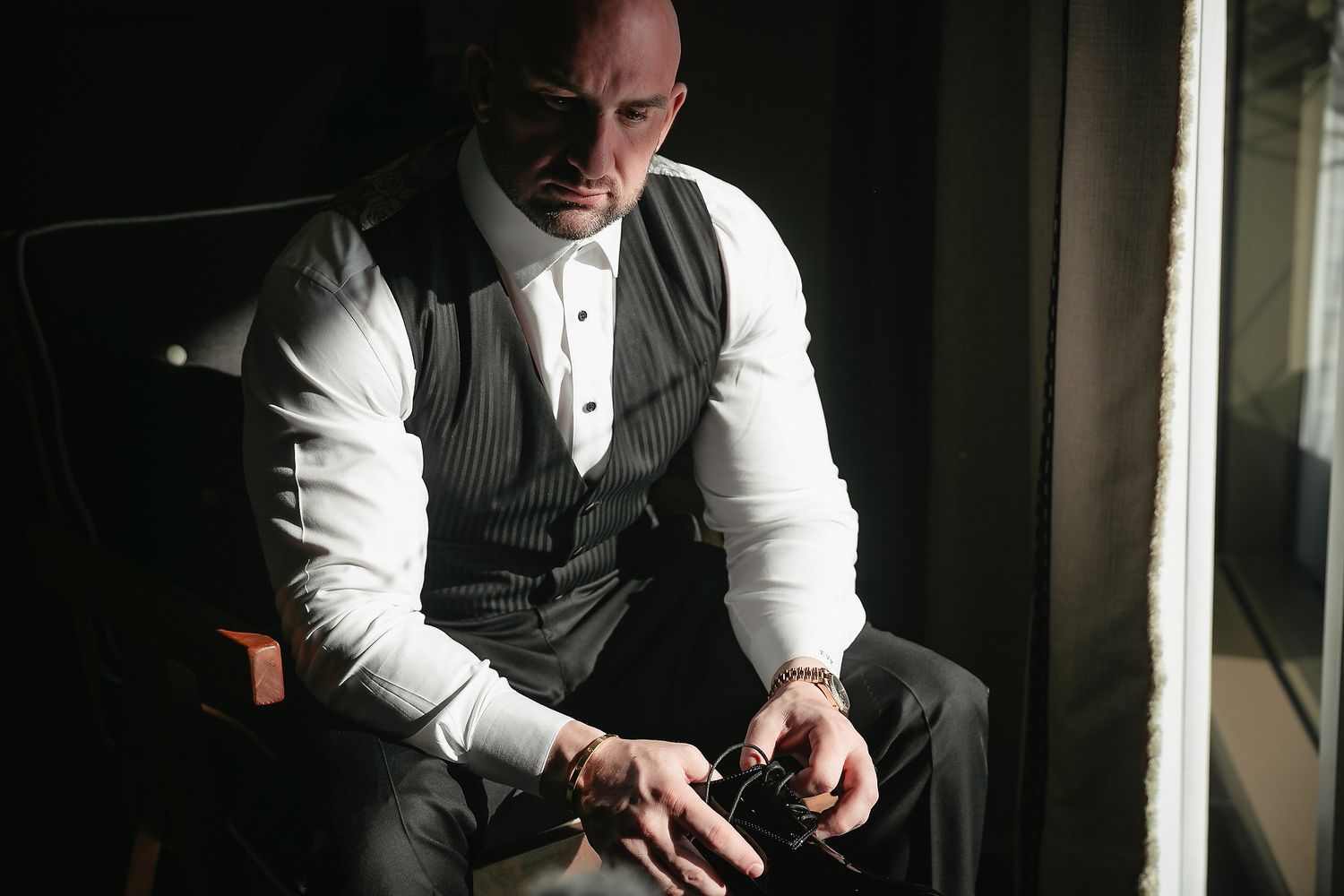 A person in formal attire adjusts their cufflinks while getting dressed.