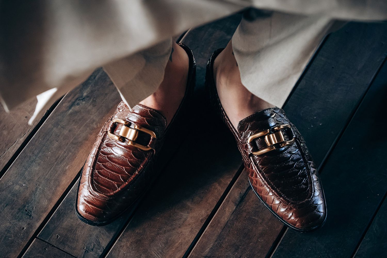 A series of brown leather dress shoes photographed from different angles on a dark wooden surface.