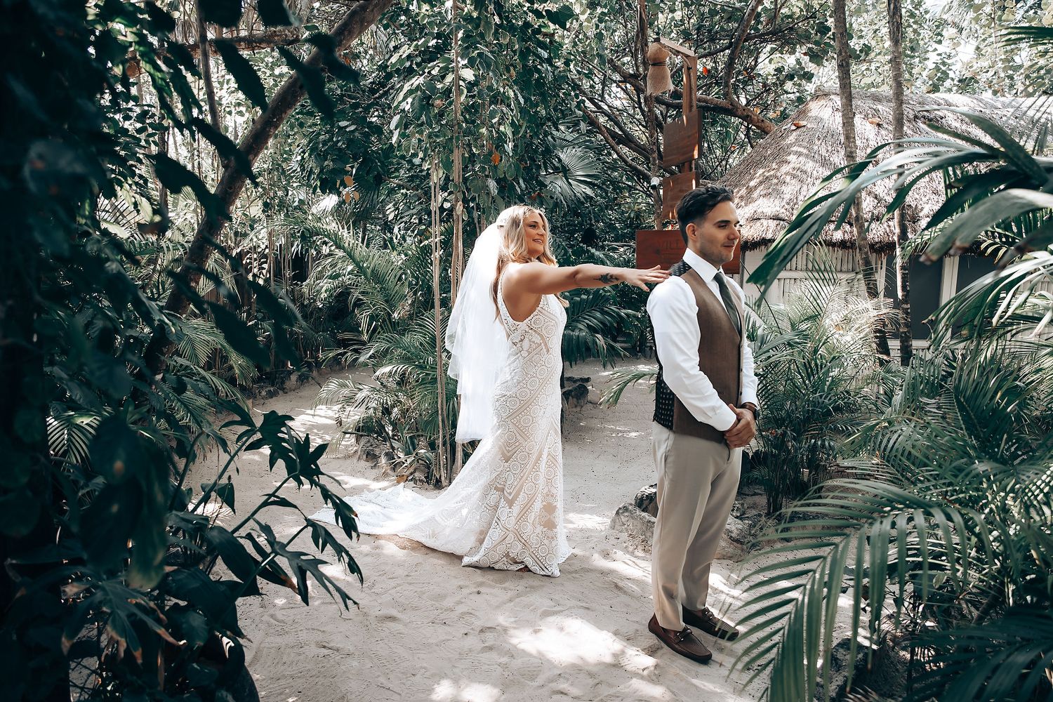 Artistic wedding photo of couple in tropical garden setting.