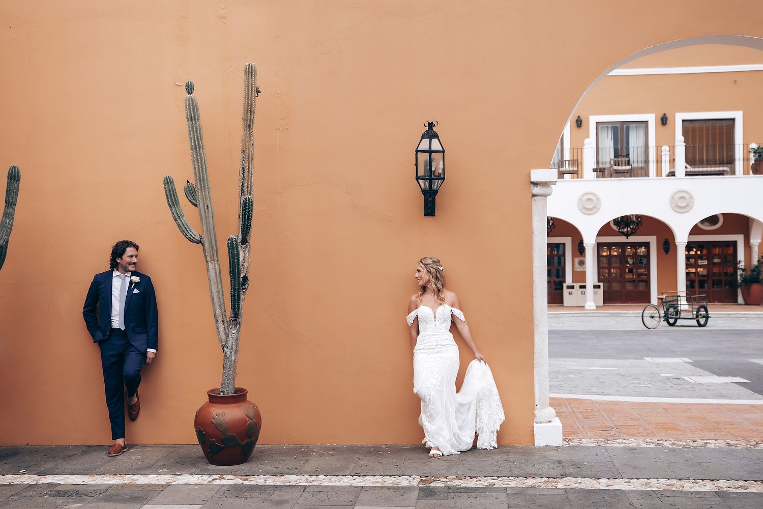 A desert-themed wedding photo session with terra cotta walls and cacti decorations.