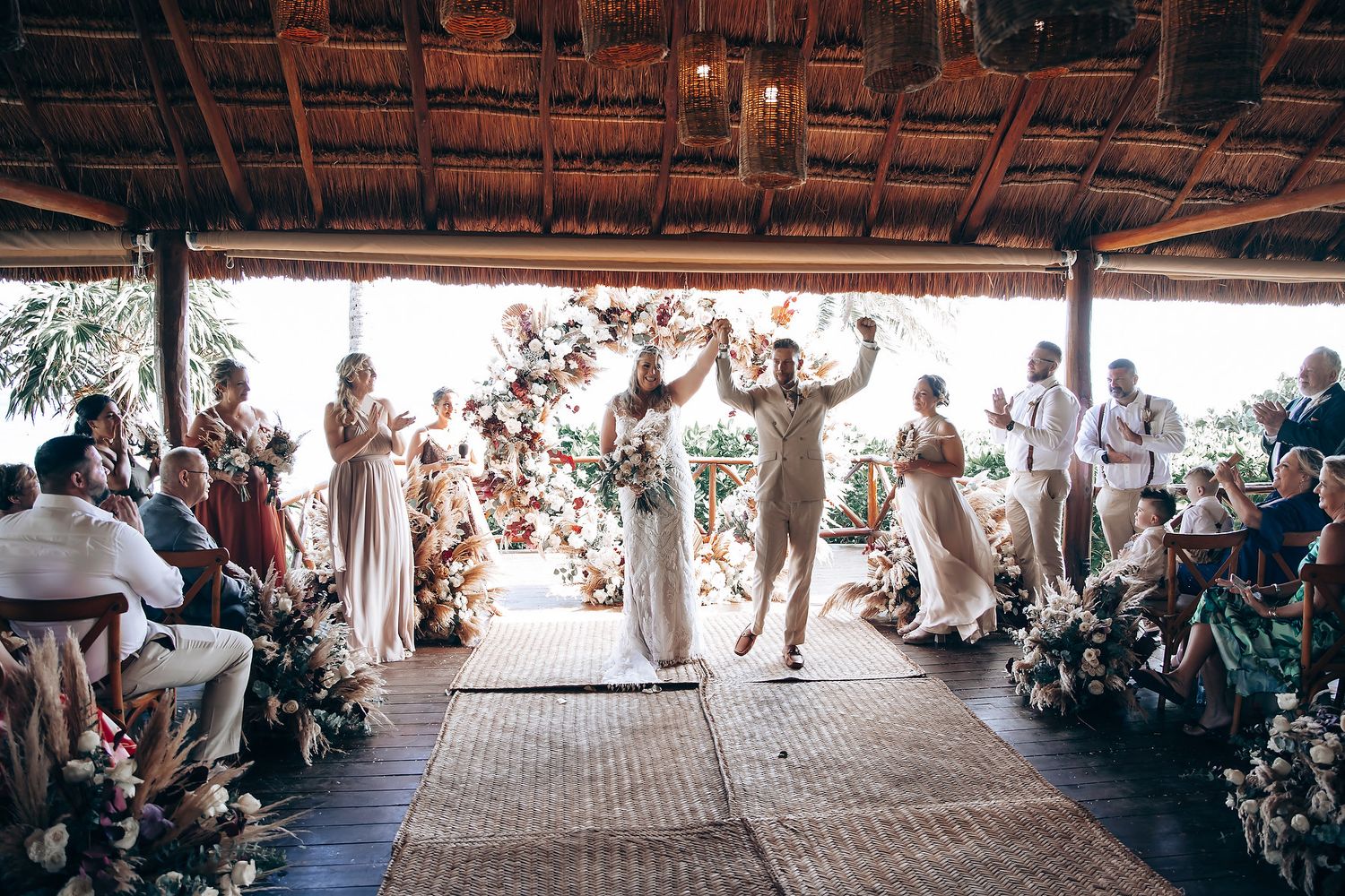 Wide angle view of an outdoor wedding celebration under a covered pavilion.