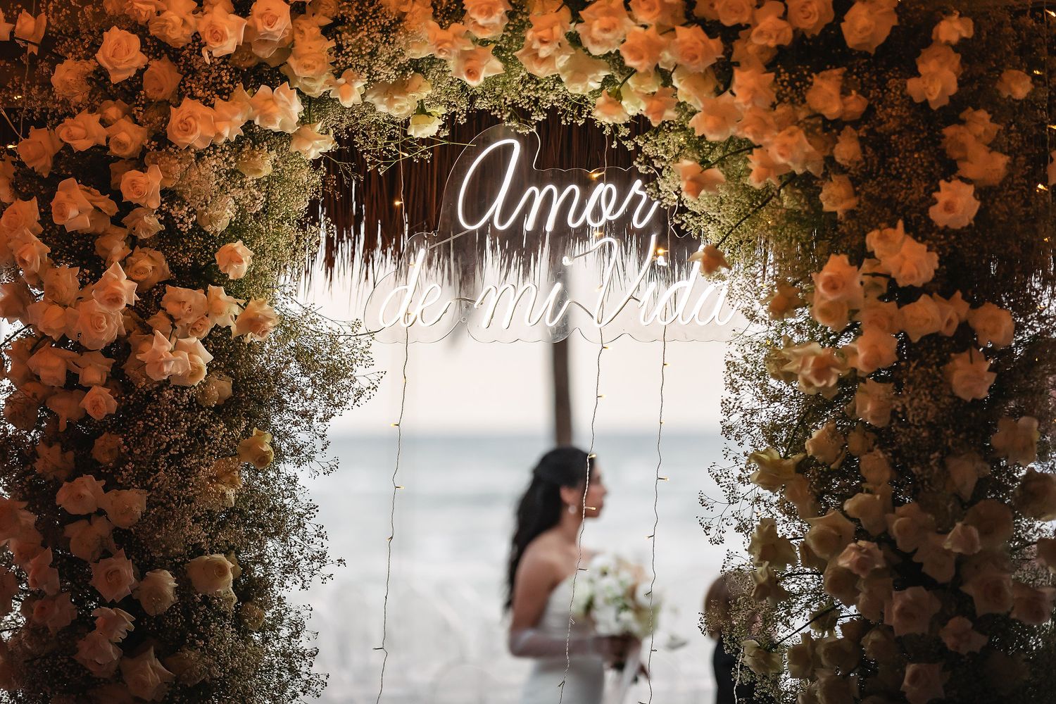 Beautiful wedding arch decorated with cascading orange and white flowers against a tropical backdrop.