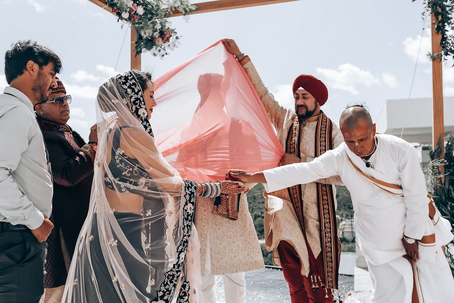 Wedding guests celebrate and dance together during an outdoor reception under a white tent canopy.