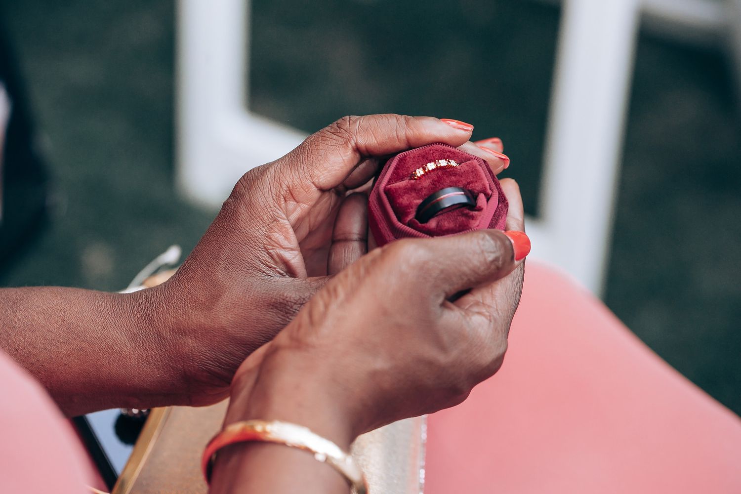 Close-up view of hands holding and examining a red glass ornament decoration.
