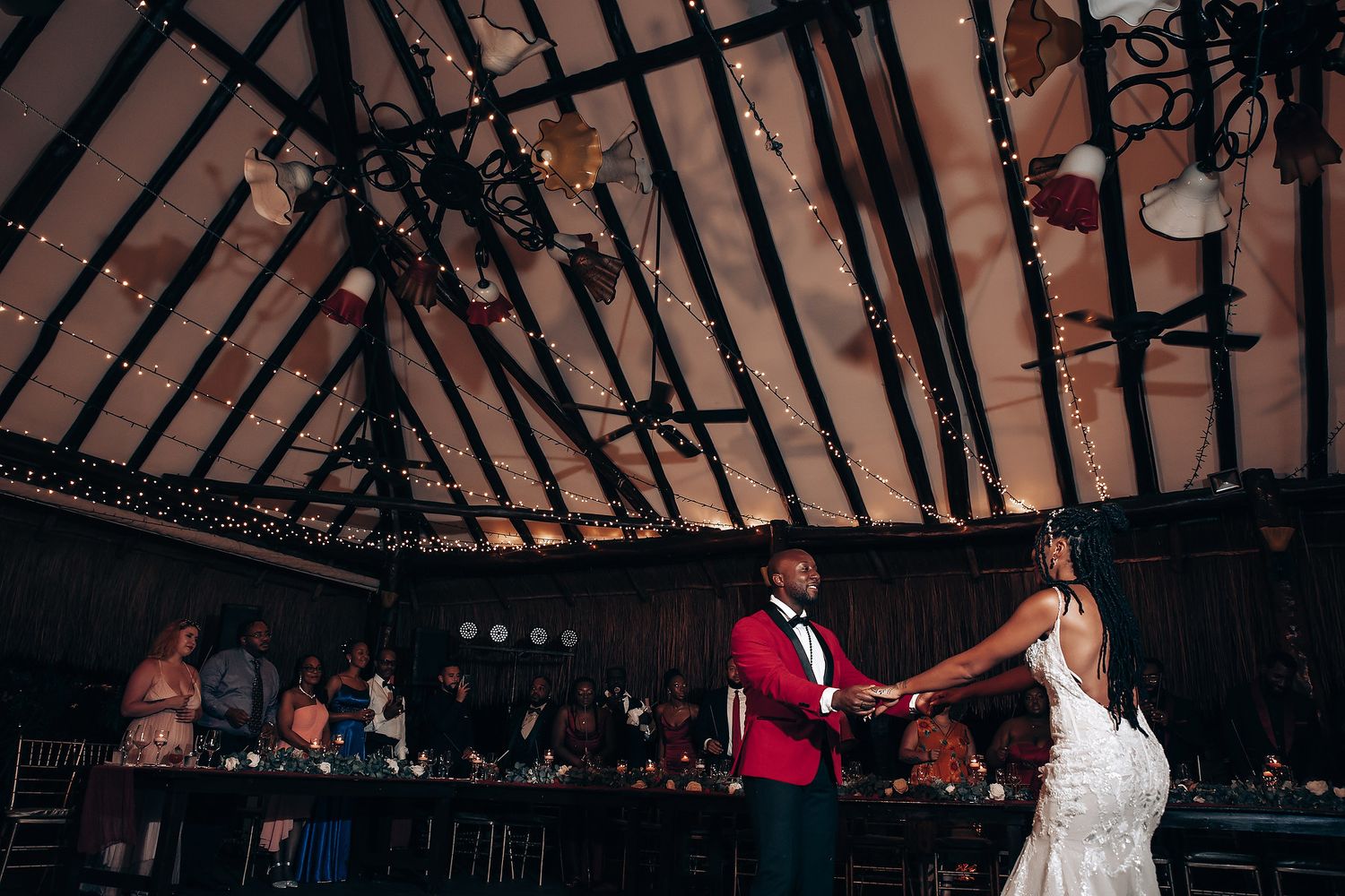 Wedding venue interior with exposed wooden beams and romantic string lights creating a warm ambiance.