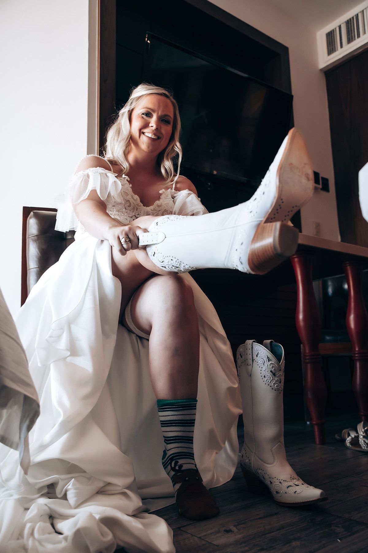 White lace boots and striped socks worn with flowing wedding dress while sitting indoors.