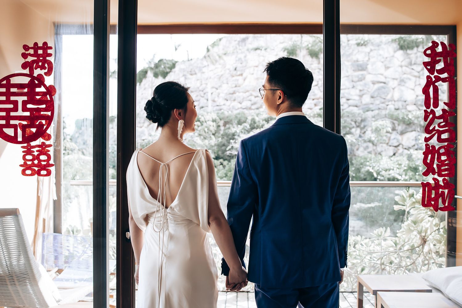 Wedding party lined up against glass windows with traditional Chinese double happiness symbols.