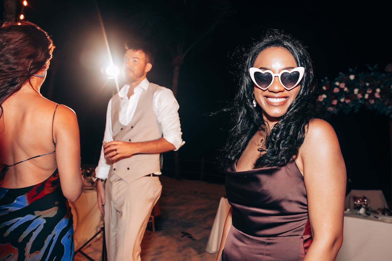 Wedding guests enjoying evening reception under string lights.