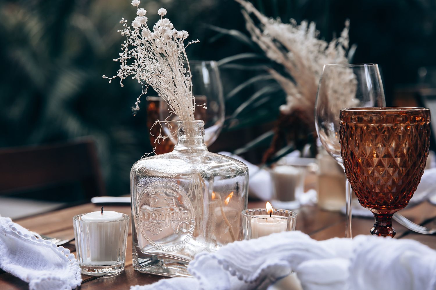 Elegant table setting with vintage glassware and white linens for a romantic outdoor dinner party.