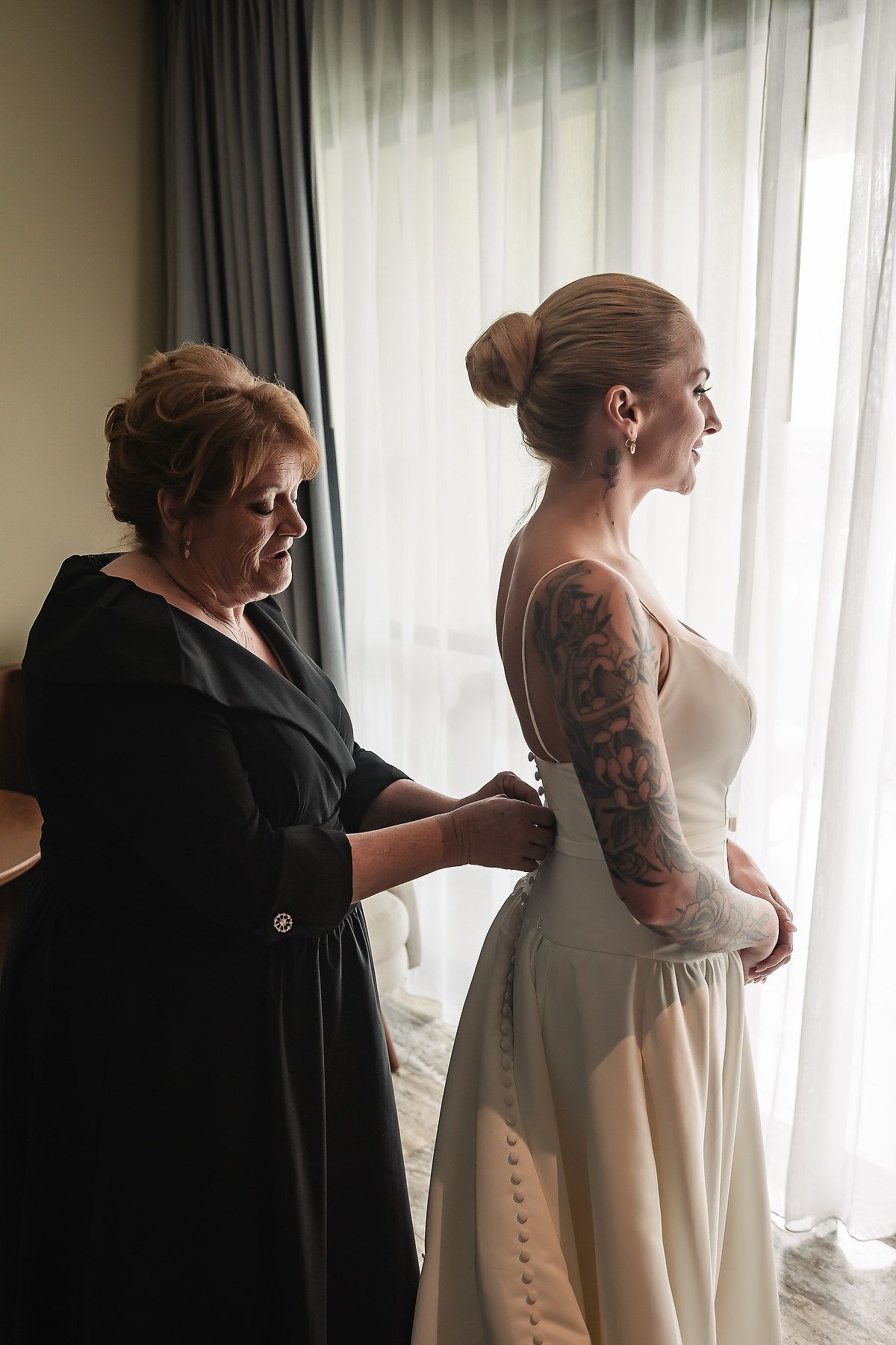 A series of intimate getting ready moments showing final wedding dress adjustments in a sunlit room.