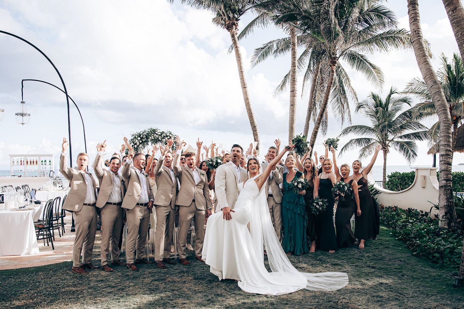 Wide angle shot of a destination wedding ceremony setup with palm trees and ocean views.