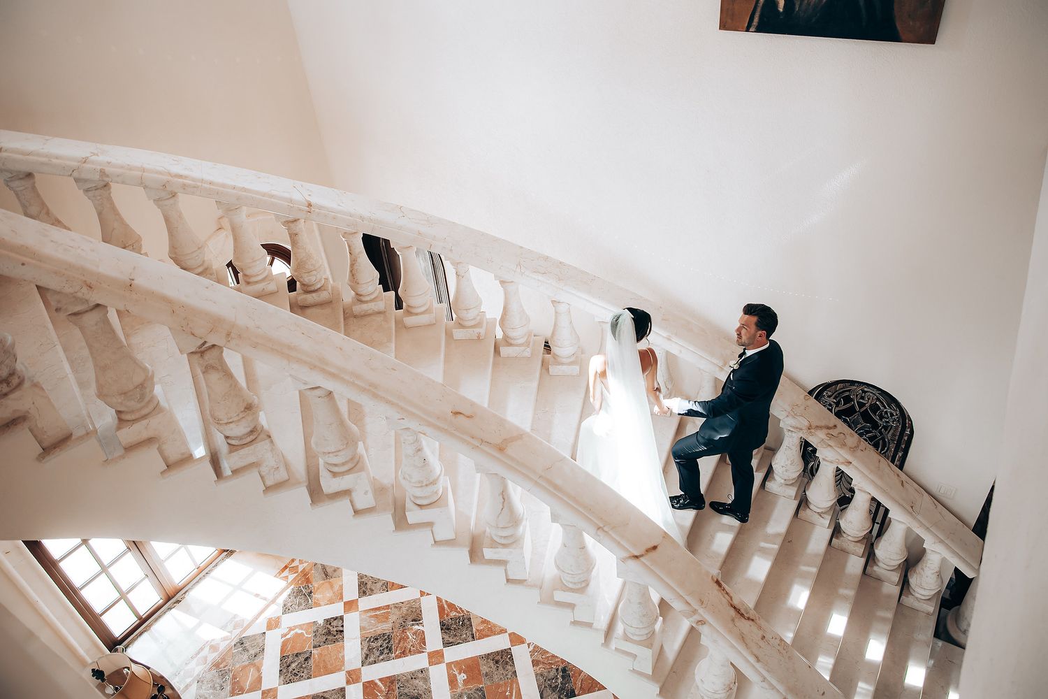 A spiral staircase with white walls and wooden steps curves upward in a modern architectural interior.