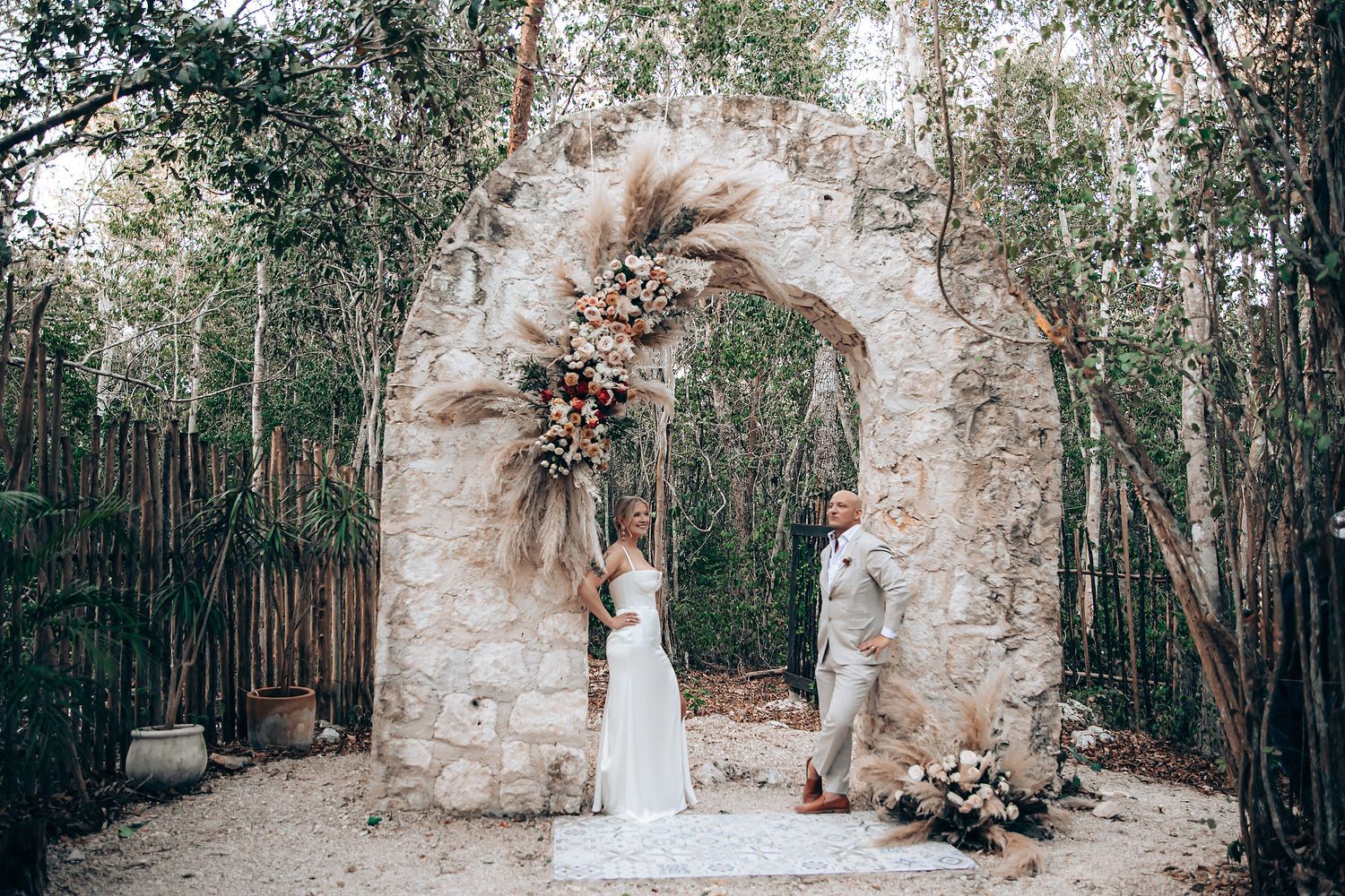 A romantic wedding venue setup in a lush forest with stone archways and greenery.
