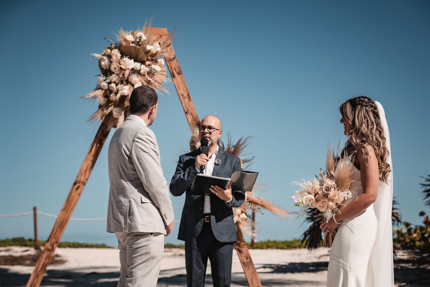 Wedding guests celebrate joyfully at an outdoor ceremony with raised arms and excited expressions.