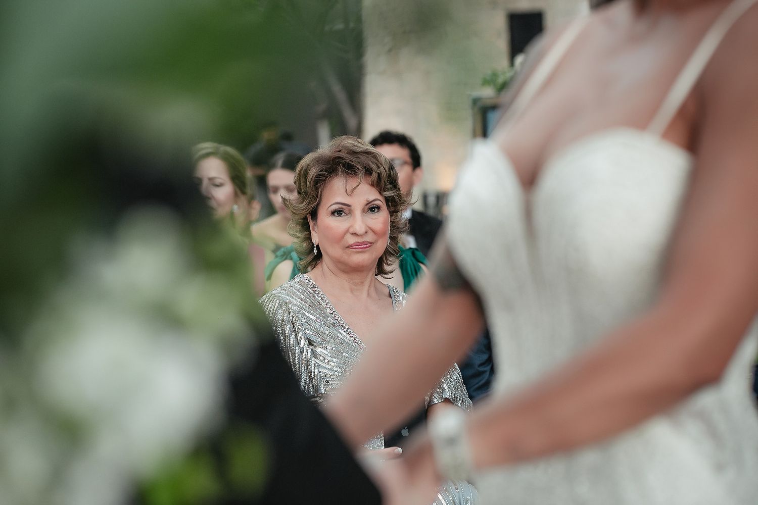 A wedding party gathers outdoors for candid photos in a lush garden setting.