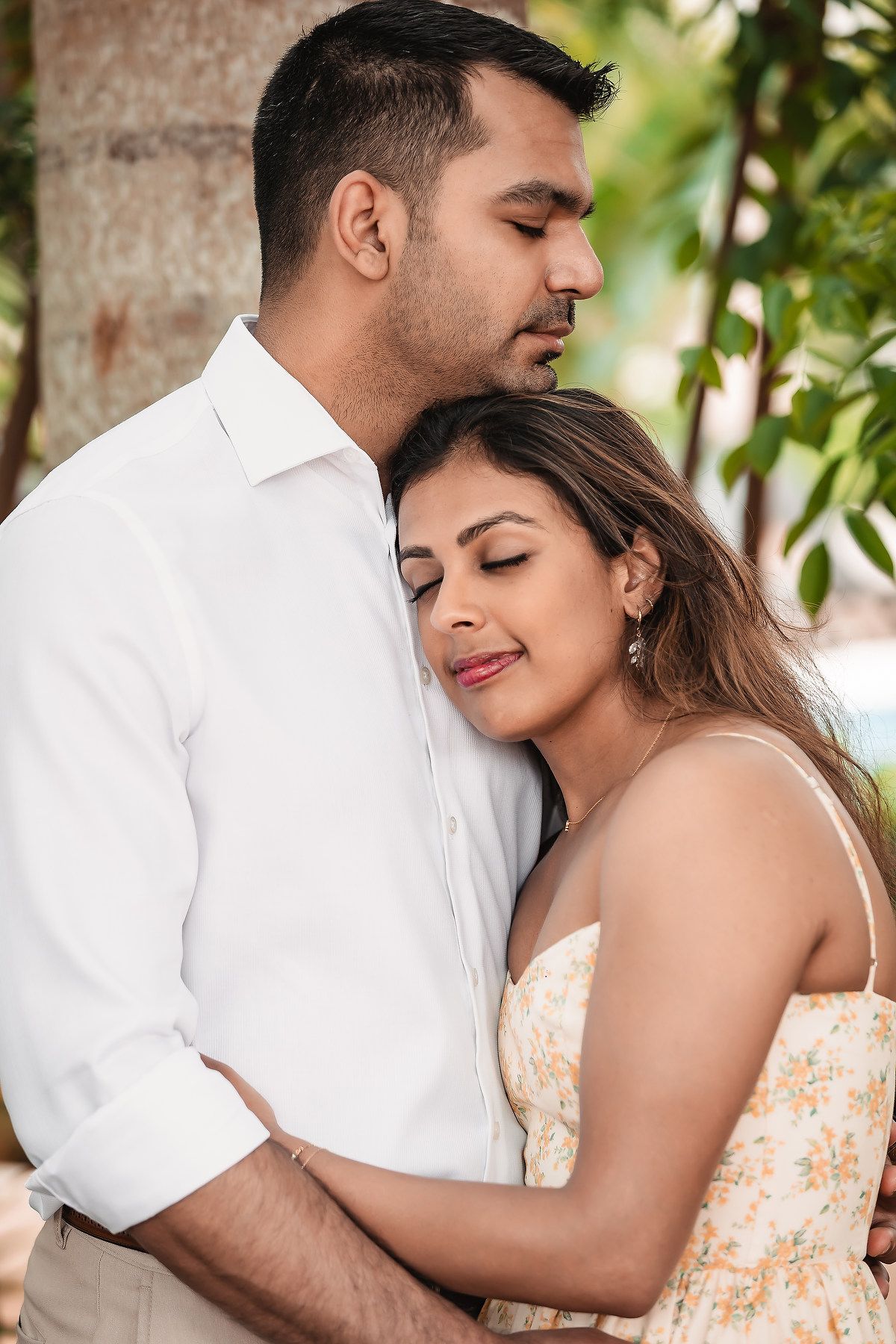 Couple in white and peach outfits embrace during outdoor photoshoot.