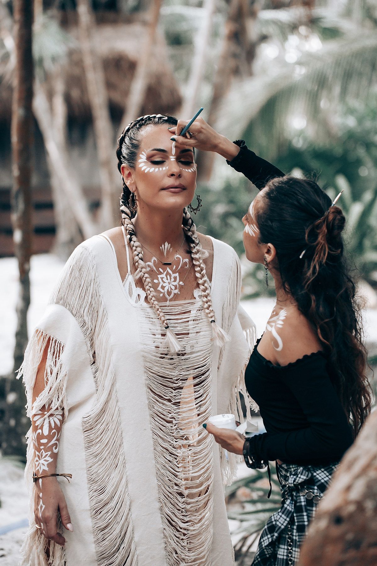 A makeup artist applies finishing touches during a tropical beach photoshoot.