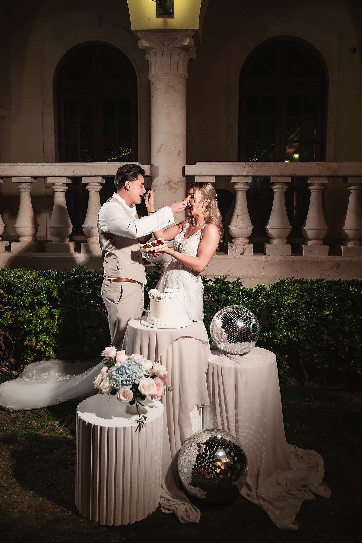 Couple shares an intimate moment at an elegant outdoor venue with white columns and romantic lighting.