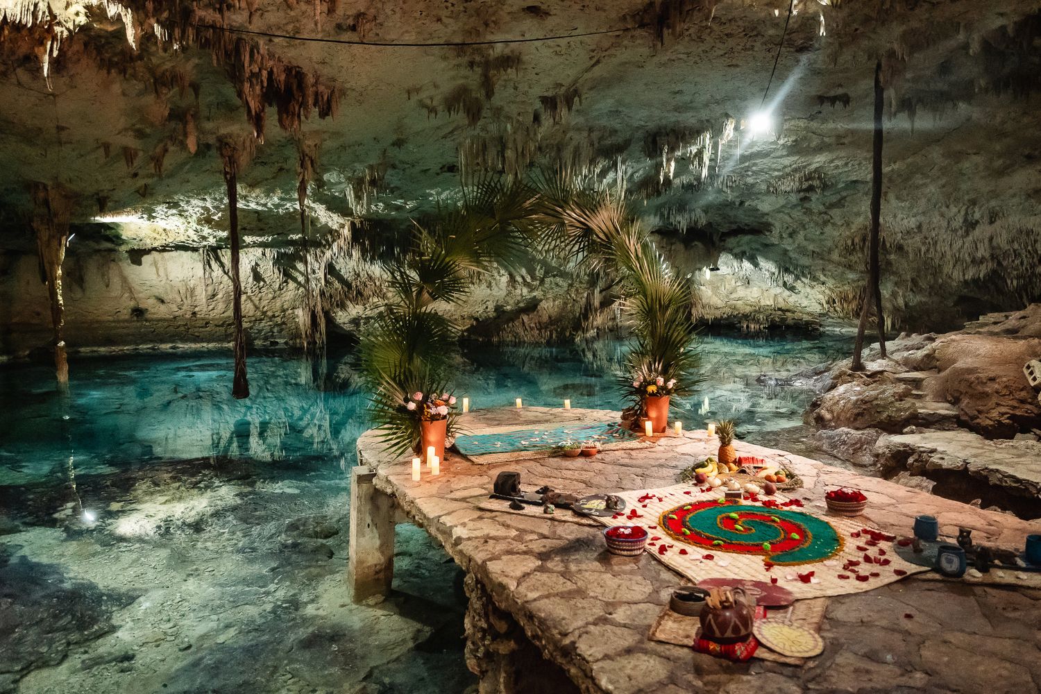 Stunning underground cenote cave with turquoise water and natural rock formations illuminated by soft lighting.