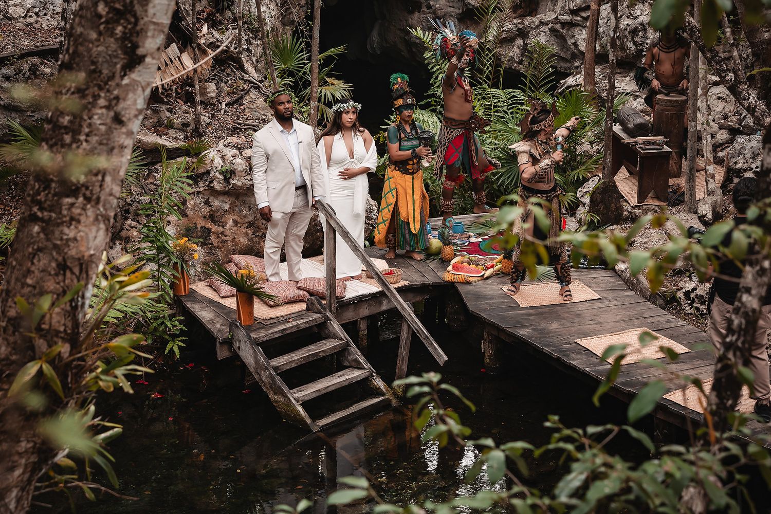 A traditional Mayan ceremony on wooden platforms in a cenote surrounded by limestone walls.