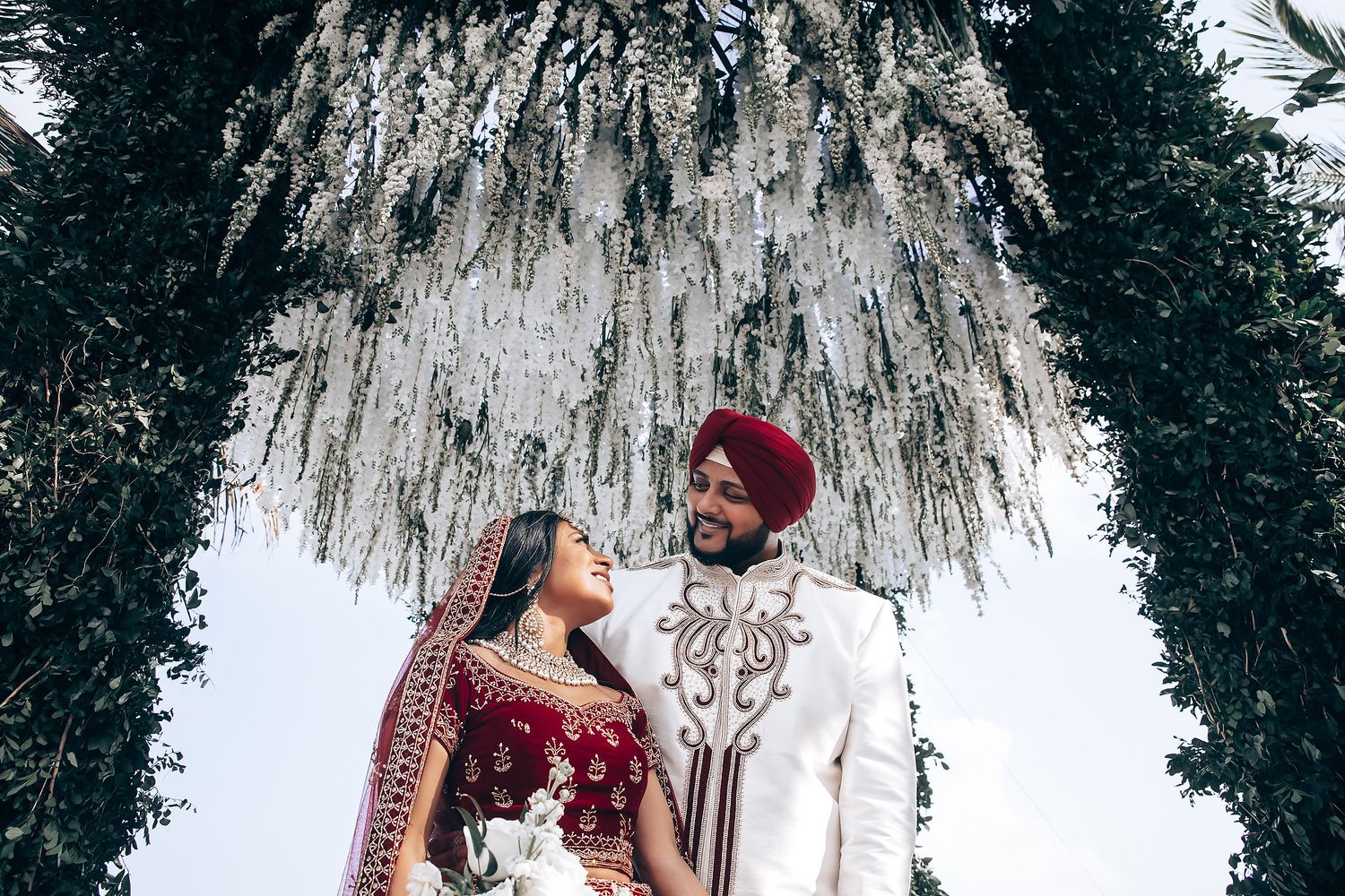 Traditional Indian wedding ceremony taking place under hanging floral decorations.