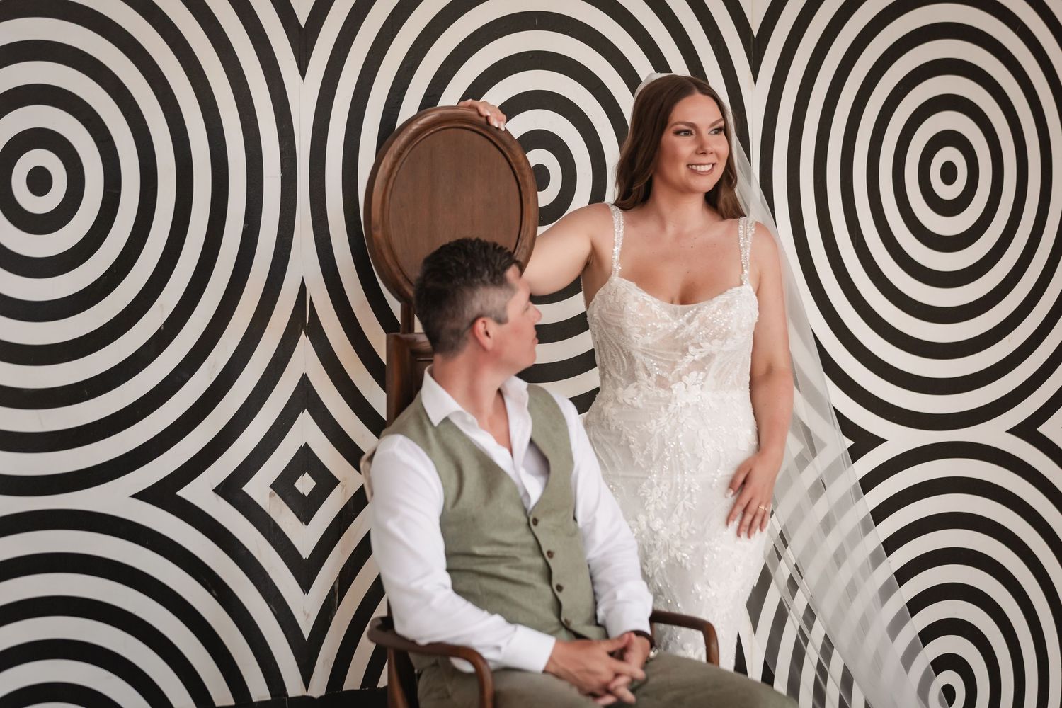 Couple shares intimate moments against a bold geometric patterned wall with modern lighting.