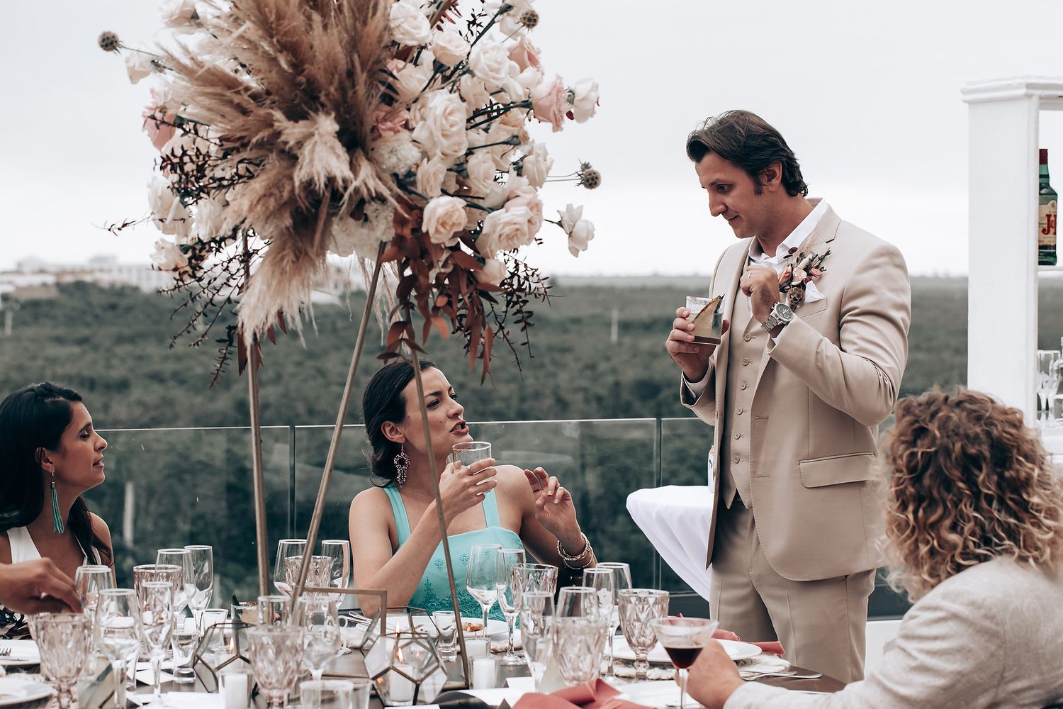 Outdoor wedding celebration with pink floral arrangements and table settings.