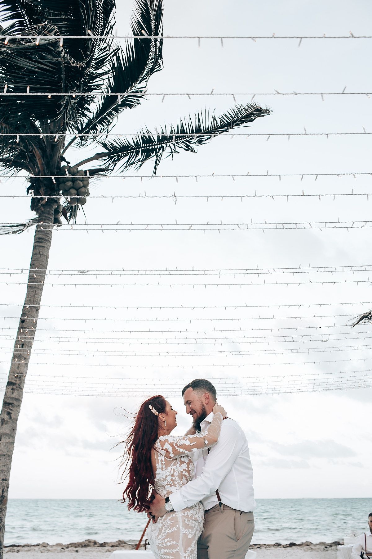 A beachside wedding setup with palm trees and string lights overlooking the ocean.