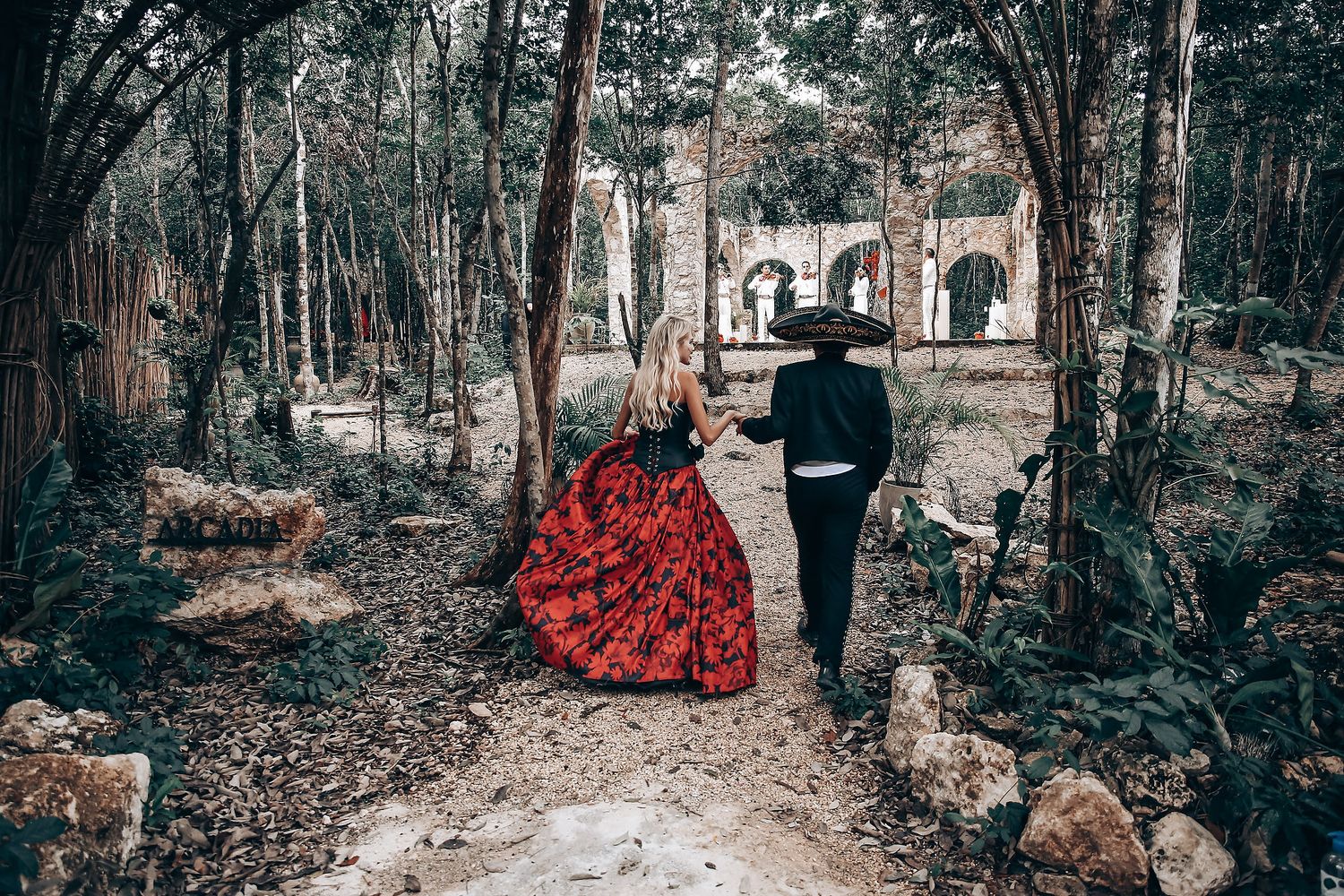 Gothic-themed wedding photoshoot in a forest with red and black color scheme.