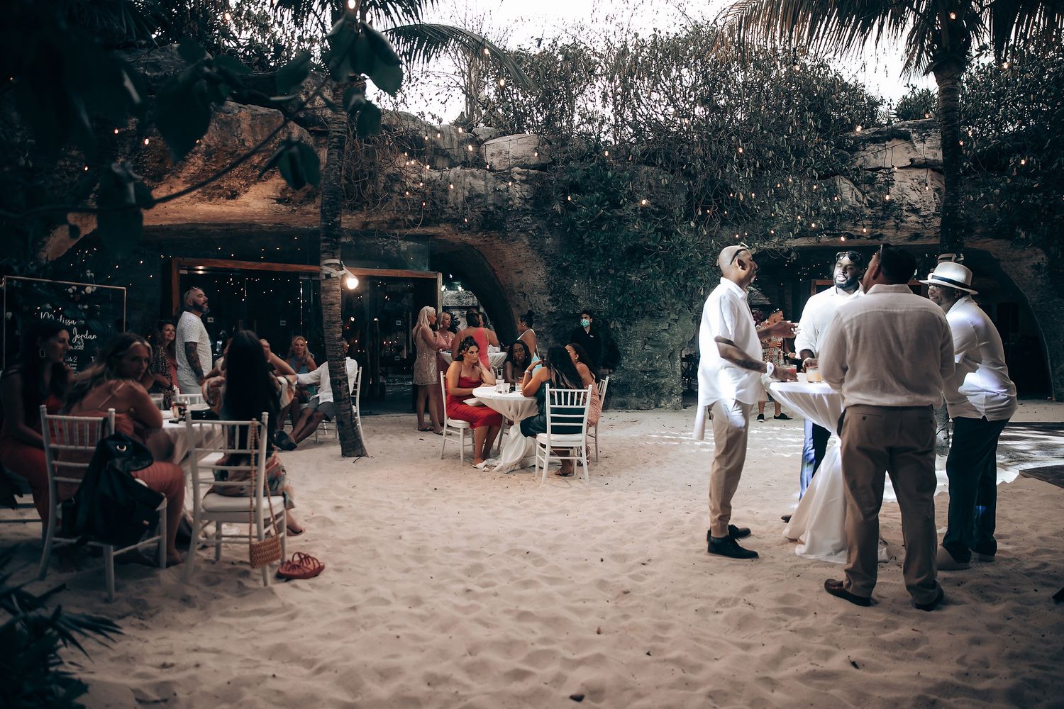 Outdoor wedding reception area with scattered seating and natural shade.