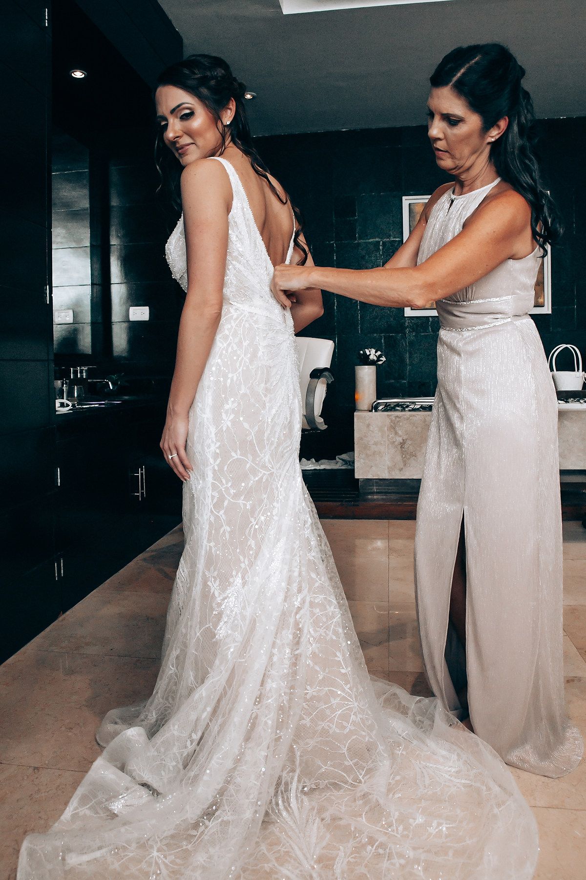 A beautiful lace wedding dress being fitted and adjusted in an elegant indoor setting.