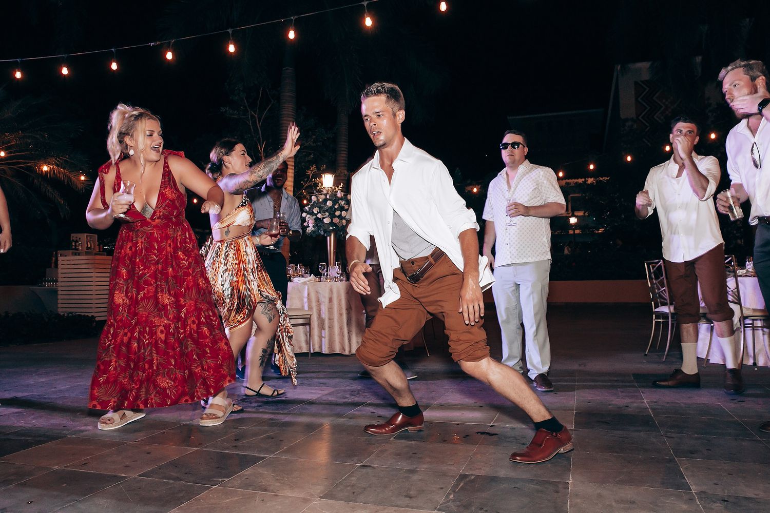 Wedding guests dancing energetically at nighttime reception.