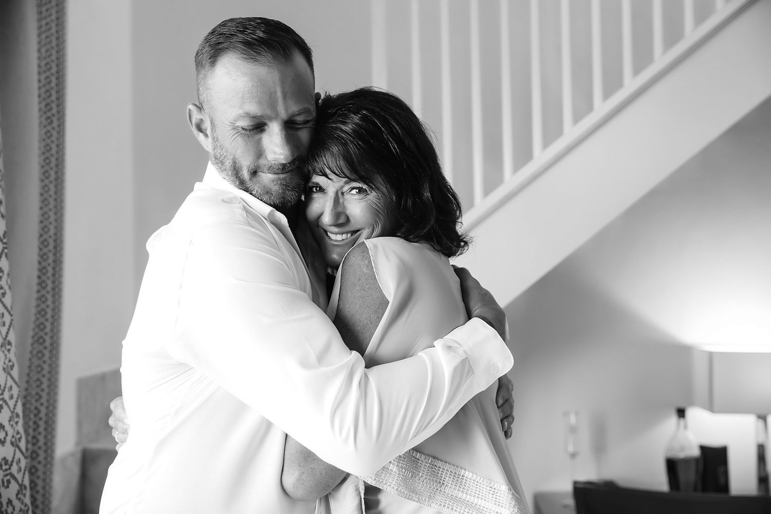 A couple embraces in a room with a large mirror.