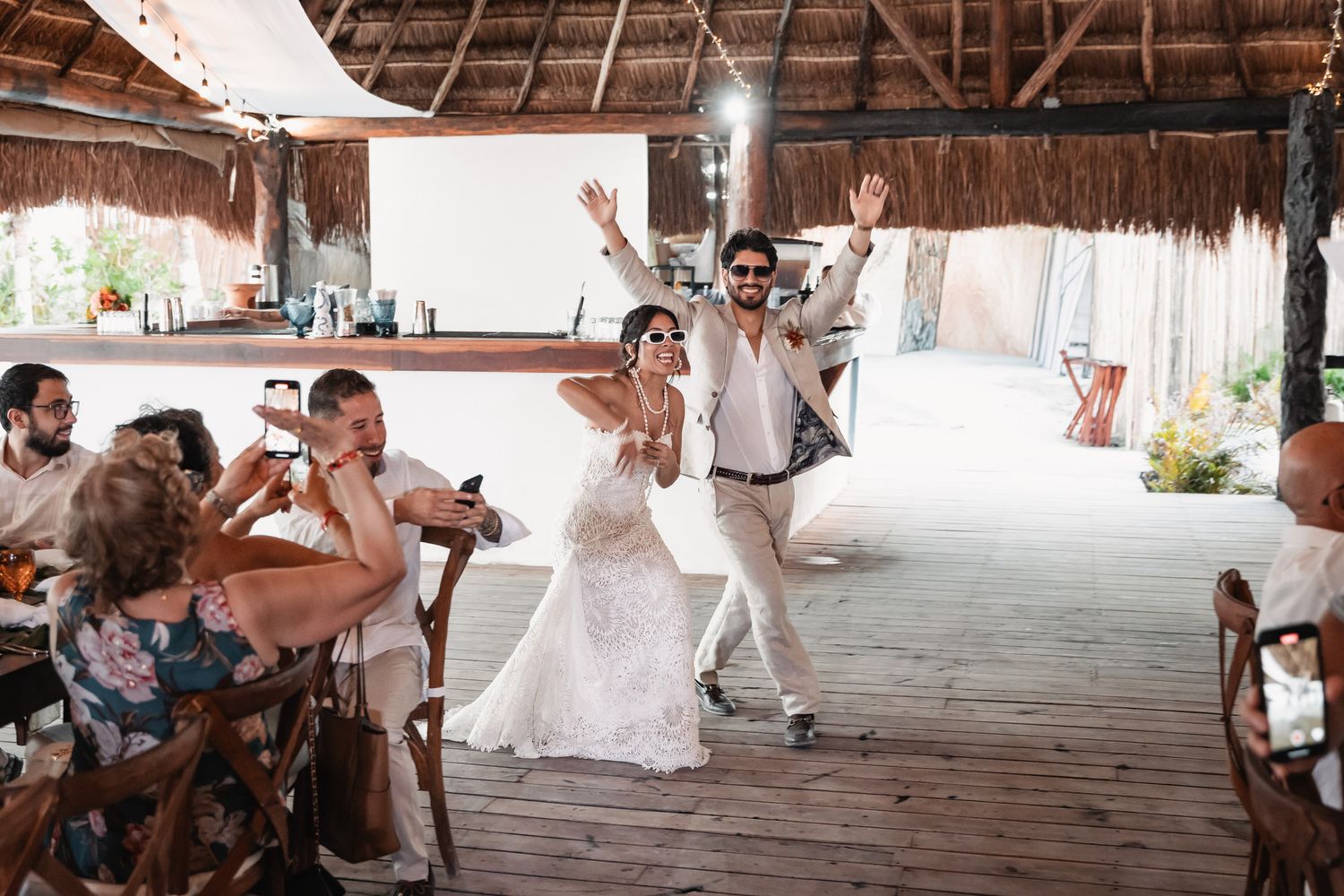 Bride and groom make grand entrance dancing at tropical open-air beach wedding reception.
