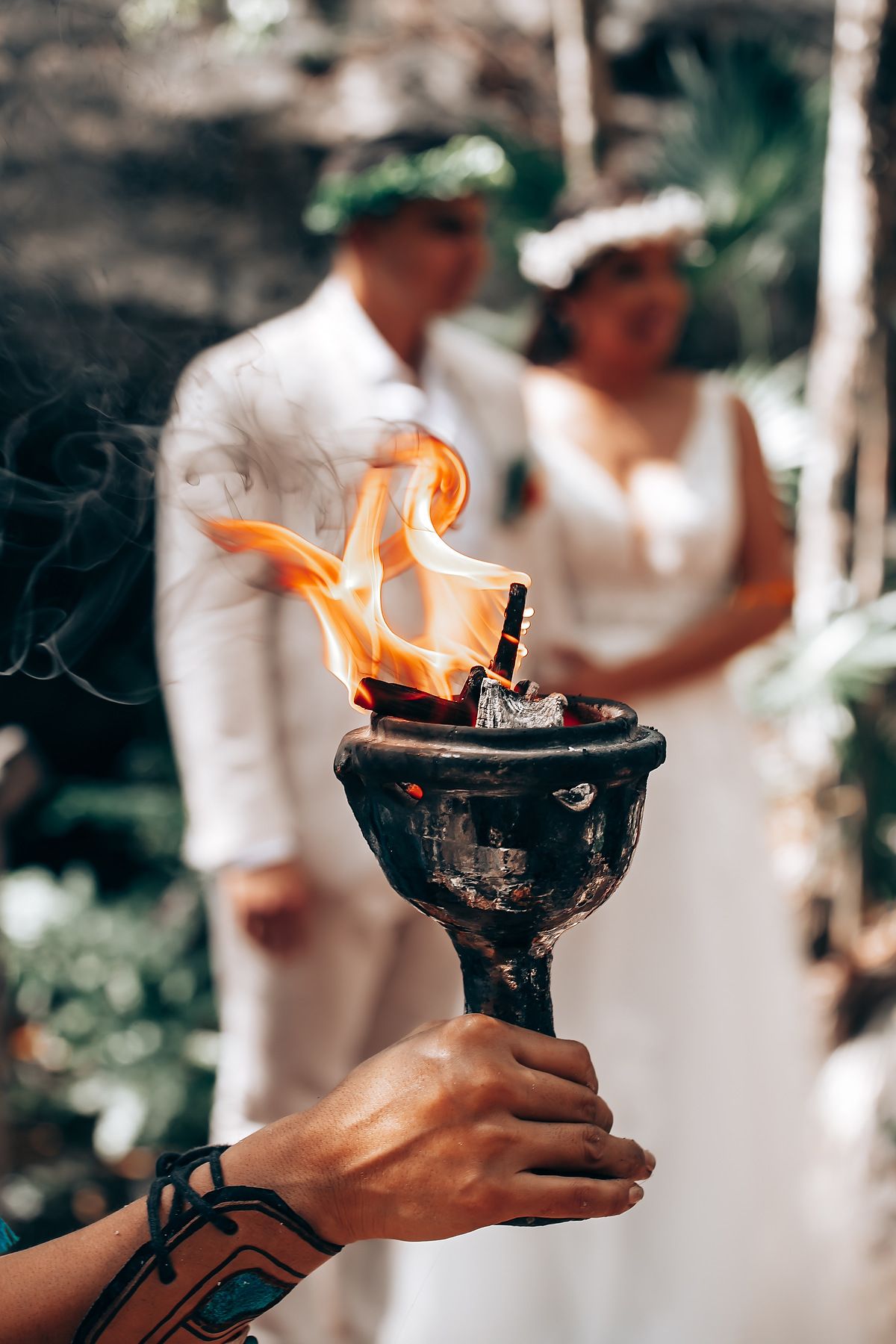 Person holding a ceremonial torch with bright orange flames during an outdoor ritual.