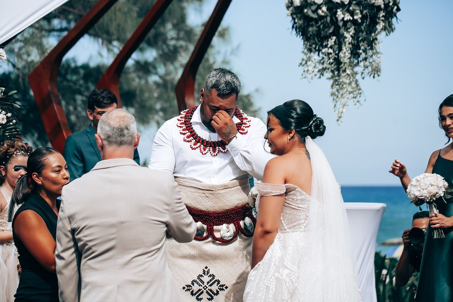 Wedding guests celebrating during an outdoor beach ceremony with tropical scenery.
