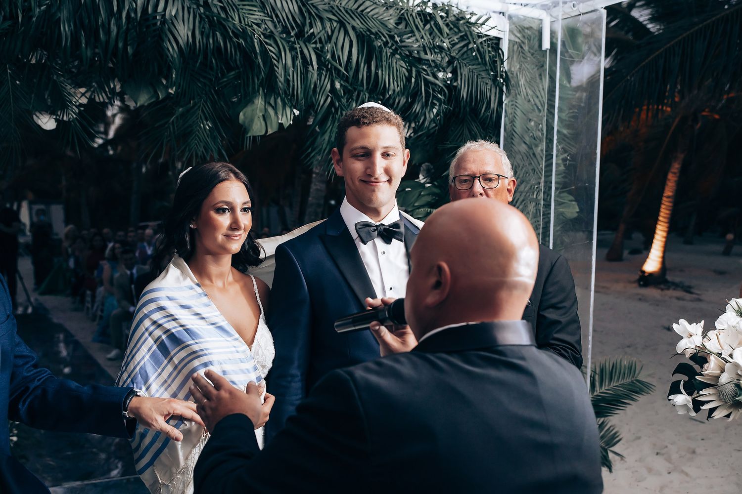 Outdoor wedding ceremony under palm trees with clear acrylic altar.