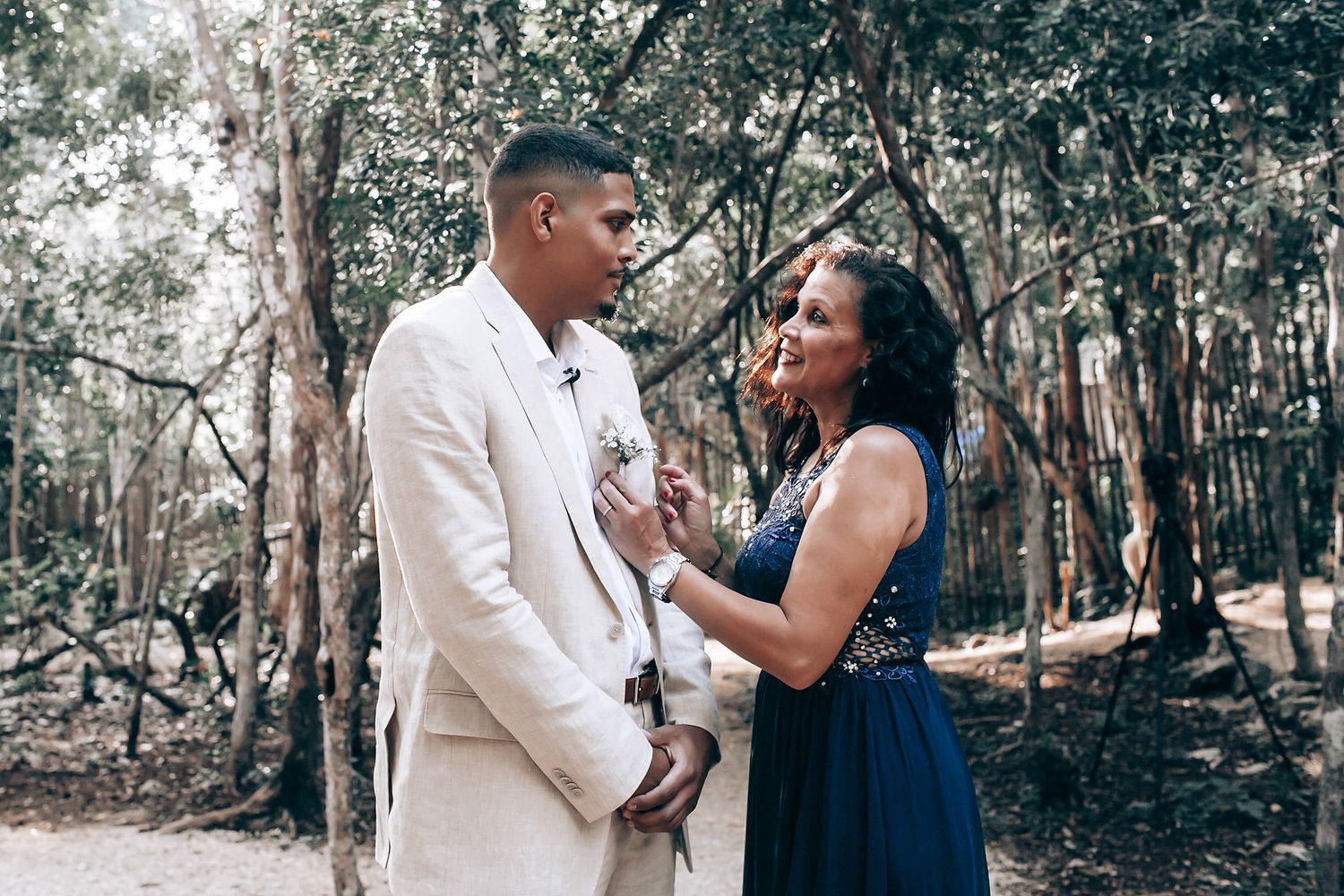 Couple sharing an intimate moment in a forest setting during a wedding ceremony.