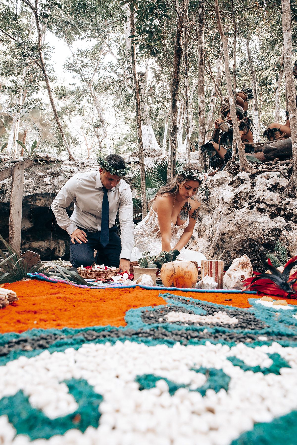 Outdoor wedding gathering with orange and teal blankets spread under eucalyptus trees.