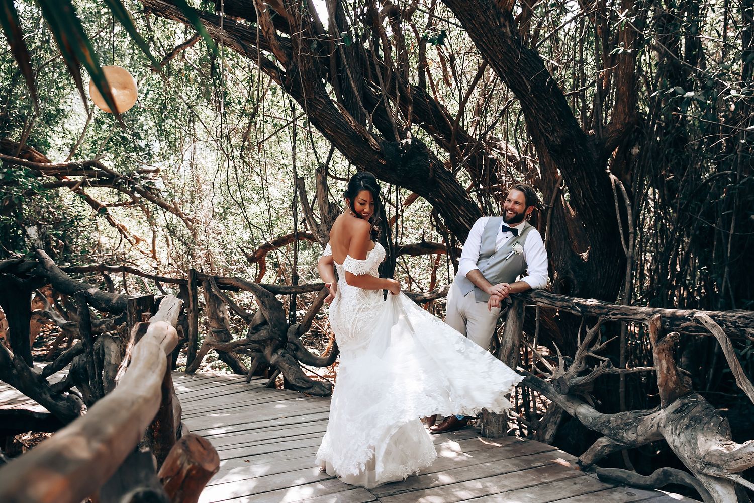 Wedding couple poses for romantic photos on a wooden boardwalk in a natural forest setting.