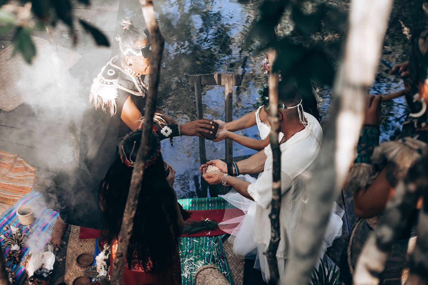 Outdoor wedding celebration with guests dancing and mingling among trees.