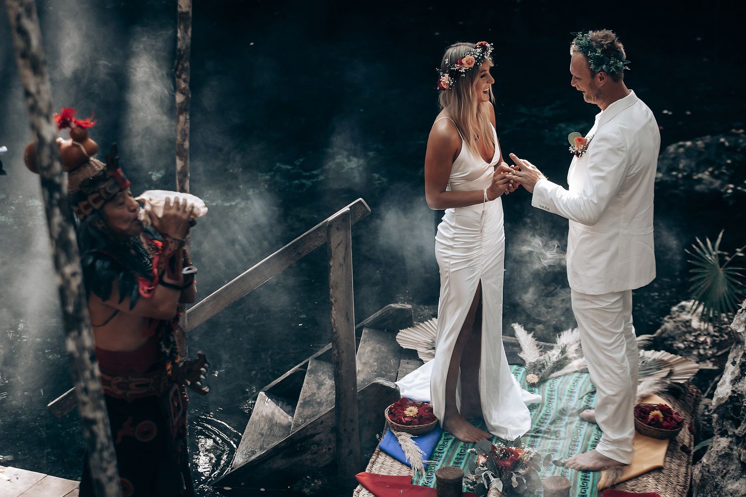 A moody forest wedding ceremony with dramatic lighting and white attire.