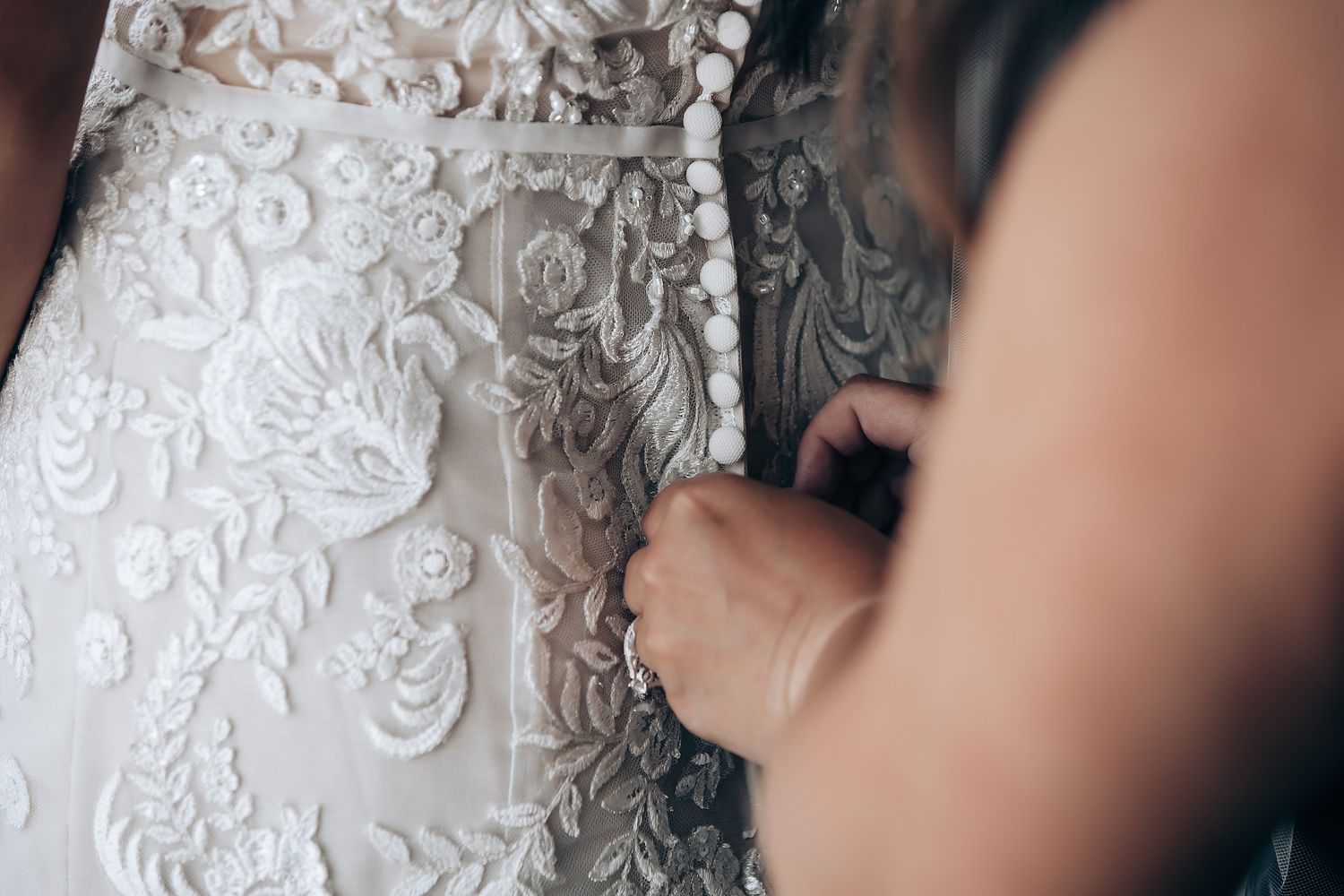 Close-up detail shots of delicate white lace and beadwork on a wedding dress.
