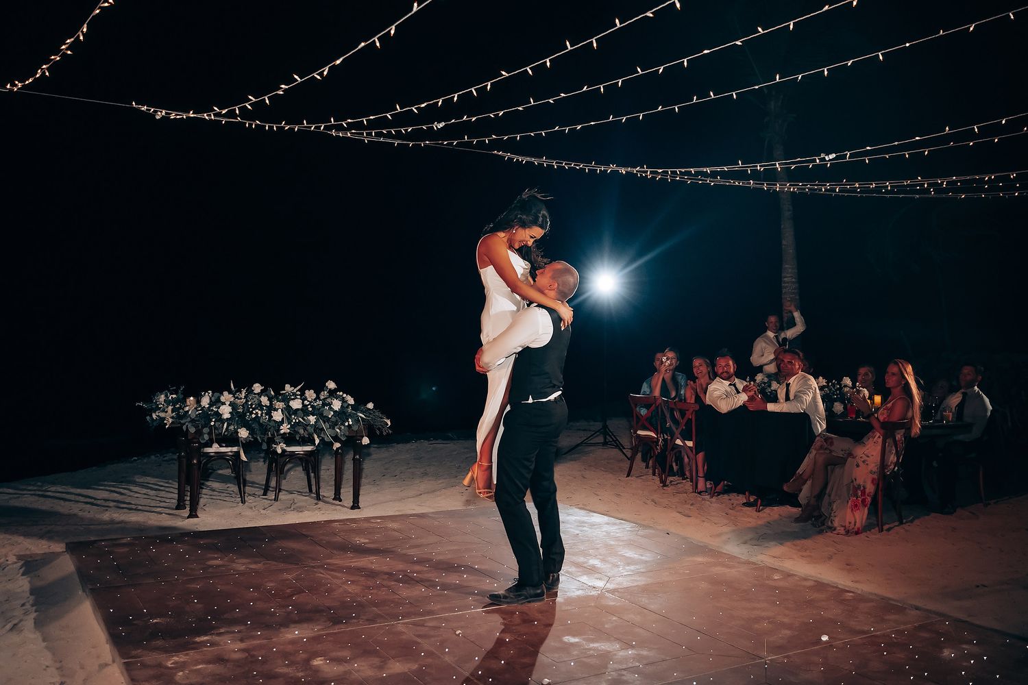 Wedding reception dance floor illuminated by string lights creating a romantic evening atmosphere.