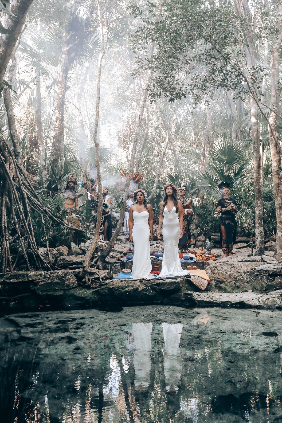 A serene outdoor wedding ceremony takes place beside a tranquil pond surrounded by misty eucalyptus trees.
