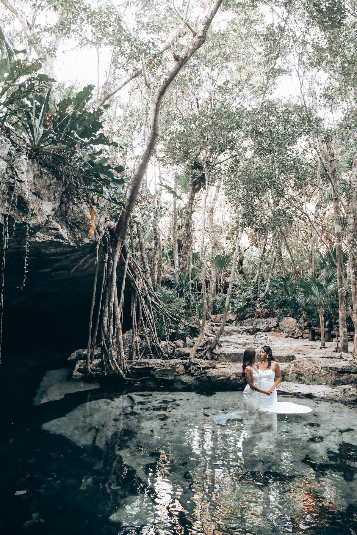 Natural cenote surrounded by lush trees creates a mystical wedding venue setting.