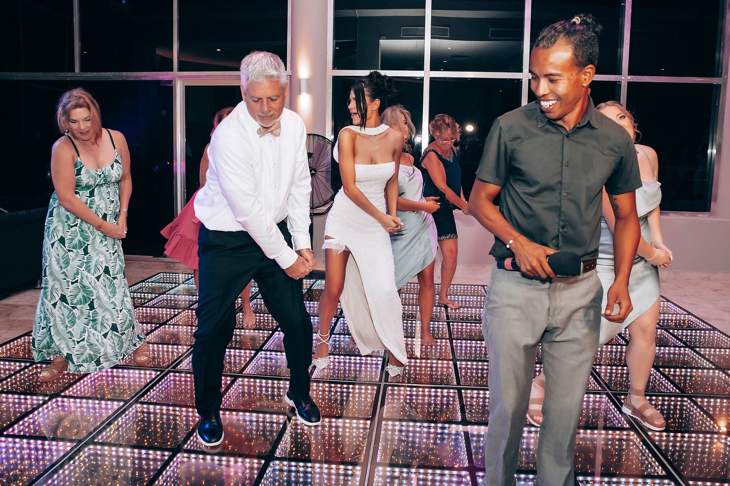 Wedding guests dance and celebrate on an illuminated LED dance floor.