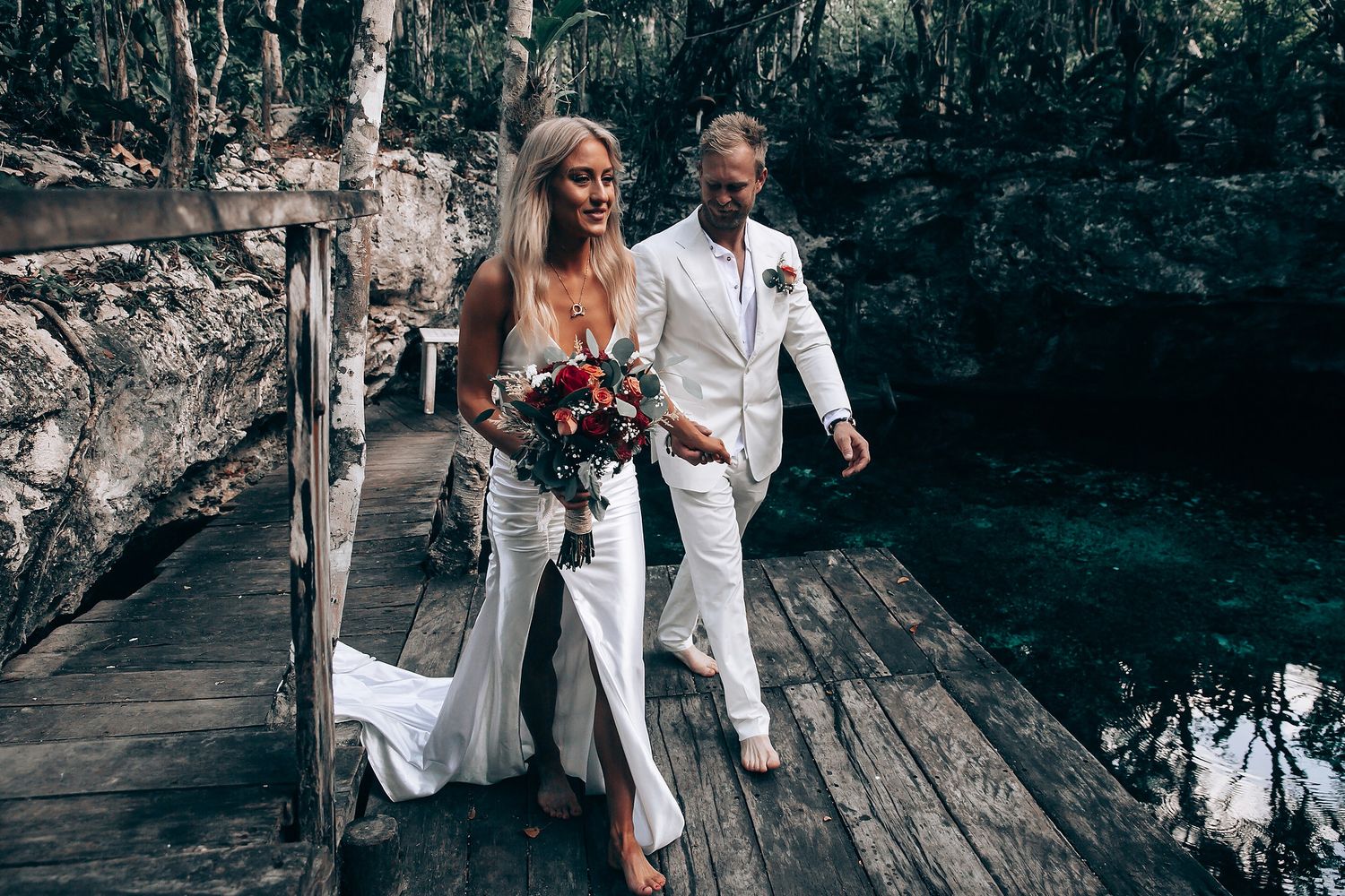 A couple stands together on a rustic wooden platform during their outdoor wedding ceremony.